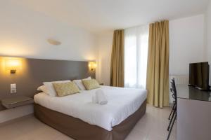 a bedroom with a large bed and a television at Hôtel Les Lentisques in Cargèse