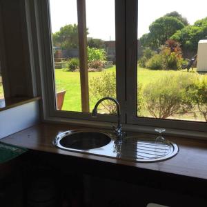a kitchen sink with a window with a view of a field at Surfside Escape in Surf Beach