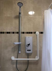 a shower in a bathroom with a phone on the wall at Budget London Room in London