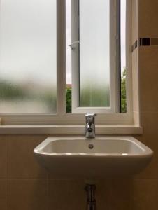 um lavatório numa casa de banho com uma janela em Budget London Room em Londres