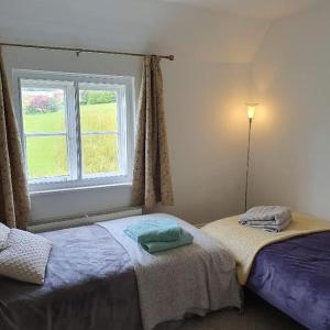 sypialnia z 2 łóżkami i oknem w obiekcie Priory Cottage w mieście Westbury