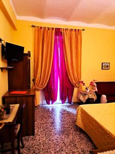 1 dormitorio con una ventana con cortinas rosas en Bed And Breakfast Camere Primavera, en Fondi