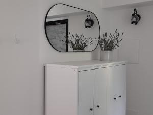espejo en la parte superior de un armario blanco en una habitación en APE BIANCA - Appartamento Lavanda, en Colico
