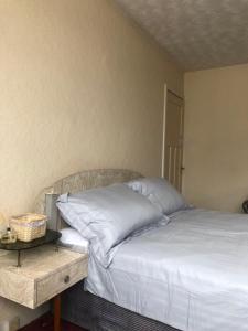 a bed with white pillows and a night stand next to it at Budget London Room in London