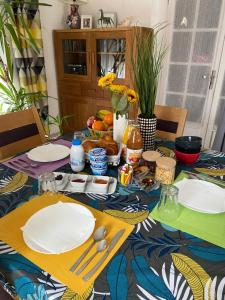 a dining table with plates and utensils on it at Chambres dans villa avec piscine in Gleizé