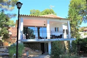 een huis met een balkon met stoelen erop bij Villa Wanderlust Sitges Hills. Exclusive pool. in Olivella