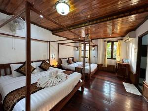 Un dormitorio con dos camas en una habitación con techos de madera. en Villa Thida Mekong Riverside, en Luang Prabang