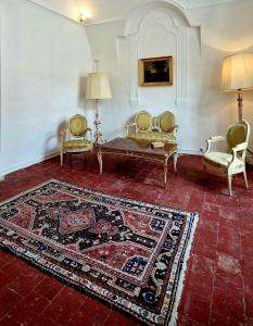 sala de estar con 2 sillas, sofá y alfombra en La tour de Pezene, en Anduze