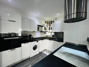 a white kitchen with a washing machine in it at Charmant deux pièces au calme in Mougins