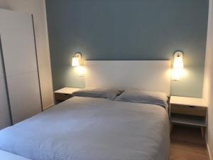 Un dormitorio con una cama blanca con dos luces. en Appartamento Piano terra Prestinone Vigezzo LT, en Santa Maria Maggiore