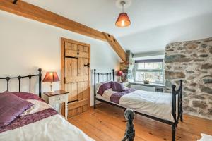 2 Betten in einem Schlafzimmer mit einer Steinmauer in der Unterkunft Ty Capel Jeriwsalem in Trawsfynydd