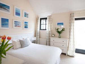 a white bedroom with a white bed and a window at Corner Cottage in Shaftesbury