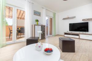 een woonkamer met een witte tafel en een televisie bij Kuća Lana in Medulin