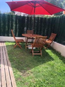 - une table de pique-nique et des chaises avec un parasol rouge dans l'établissement El Gurugú, apartamento con jardín en la playa de Barro, à Barro de Llanes