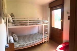 two bunk beds in a room with a window at El Gurugú, apartamento con jardín en la playa de Barro in Barro de Llanes