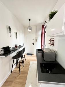 a kitchen with a sink and a counter with stools at Le JOY, studio au coeur de la ville in Beauvais