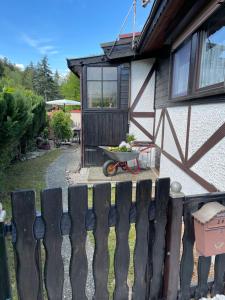 einen Zaun vor einem Haus mit einer Schubkarre in der Unterkunft Ferienhaus Sternschnuppe in Limbach
