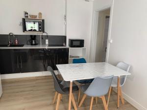 a dining room with a white table and chairs at Charmant logement à 2 pas de la plage in Le Portel