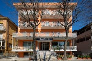 un edificio arancione con un balcone e due alberi di Hotel Ravello da Lorenzo e Moira a Rimini