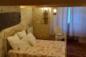 um quarto com uma cama com almofadas e uma cadeira em Bella Vista em Aubeterre-sur-Dronne