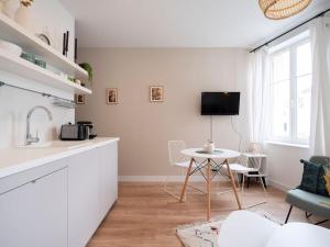 uma cozinha branca com uma mesa e uma televisão em Le Coquet des Trois-Maisons avec parking privatif em Nancy