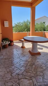 un patio con mesa y suelo de piedra en Apartmani Lucia en Rab