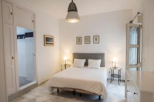 Dormitorio blanco con cama y puerta de cristal en La Casa de Lucía en Ayamonte