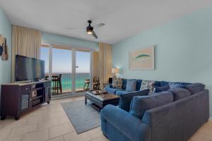 uma sala de estar com um sofá azul e uma televisão em Leeward Key 903 em Destin