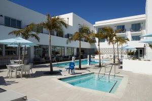 uma piscina com palmeiras e um edifício em Courtyard by Marriott Santa Barbara Downtown em Santa Bárbara