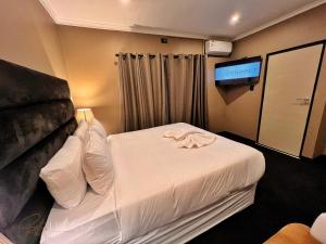 a hotel room with a bed and a flat screen tv at St Tropez Guest House in Phuthaditjhaba