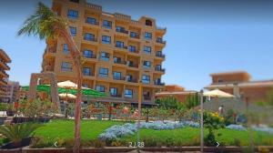 un grande edificio giallo con un giardino di fronte di My Sky Sea View 1 Bedroom Apartment a Hurghada