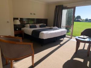 a bedroom with a bed and a large window at Admirals Motor Inn in Nelson
