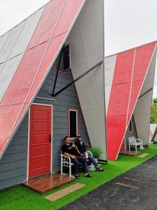 two people sitting on a chair in front of a house at Red Triangle Cottage Roomstay in Kampong Kemaman