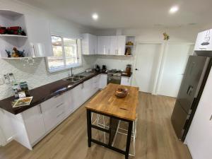 a kitchen with white cabinets and a wooden table at Preston Valley Country Cabin in Lowden