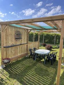 a picnic table and chairs under a wooden pergola at GITE les cactus logement indépendant 