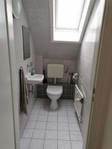 een badkamer met een toilet, een wastafel en een raam bij Ferienwohnung Abby in Butjadingen