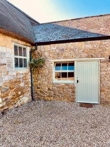 Casa de piedra con puerta blanca y ventanas en Grange stables, en North Cadbury