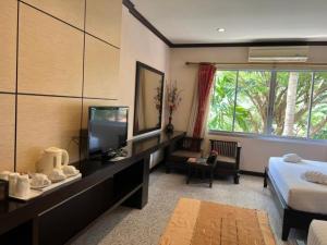 a hotel room with a bed and a tv and a bedroom at Lotus Paradise Resort - SHA PLUS in Koh Tao