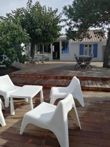 eine Gruppe von weißen Tischen und Stühlen auf einer Terrasse in der Unterkunft nataliledeco bed and breakfeast in La Guérinière