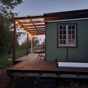 un porche de una casa con una terraza con una mesa en Bellingen Hideaway Tiny Home- Breathe. Discover. Renew., en Bellingen