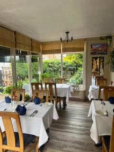 a restaurant with white tables and chairs and windows at Villa Bianca B&B in Penrith