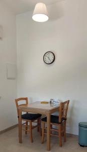 einen Tisch mit Stühlen und eine Uhr an der Wand in der Unterkunft נצר- צימר 