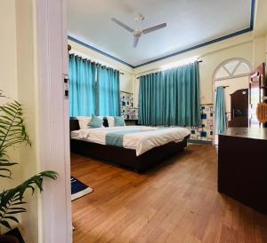 - une chambre avec un grand lit et des rideaux bleus dans l'établissement Himalayan Guest House, à Pokhara