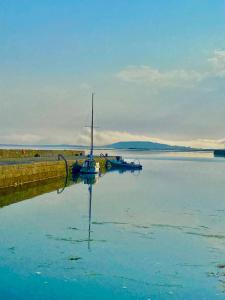 a sail boat sitting in the water next to a dock at Oranuisce Thatch Cottage Ballyvaughan in Ballyvaughan