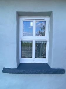 a window in a white wall with a blue cushion at Oranuisce Thatch Cottage Ballyvaughan in Ballyvaughan