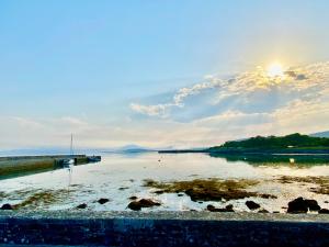a view of a body of water with the sun in the sky at Oranuisce Thatch Cottage Ballyvaughan in Ballyvaughan