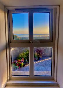 a window with a view of the ocean through it at Oranuisce Thatch Cottage Ballyvaughan in Ballyvaughan