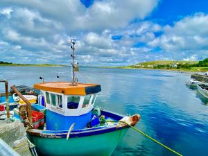 a boat is docked at a dock in the water at Oranuisce Thatch Cottage Ballyvaughan in Ballyvaughan