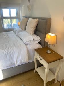 a bed with white sheets and a table with a lamp at Oranuisce Thatch Cottage Ballyvaughan in Ballyvaughan