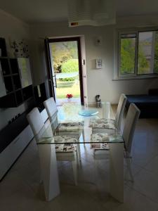 una sala da pranzo con tavolo in vetro e sedie bianche di La Terrazza Sul Lago a Ossuccio
